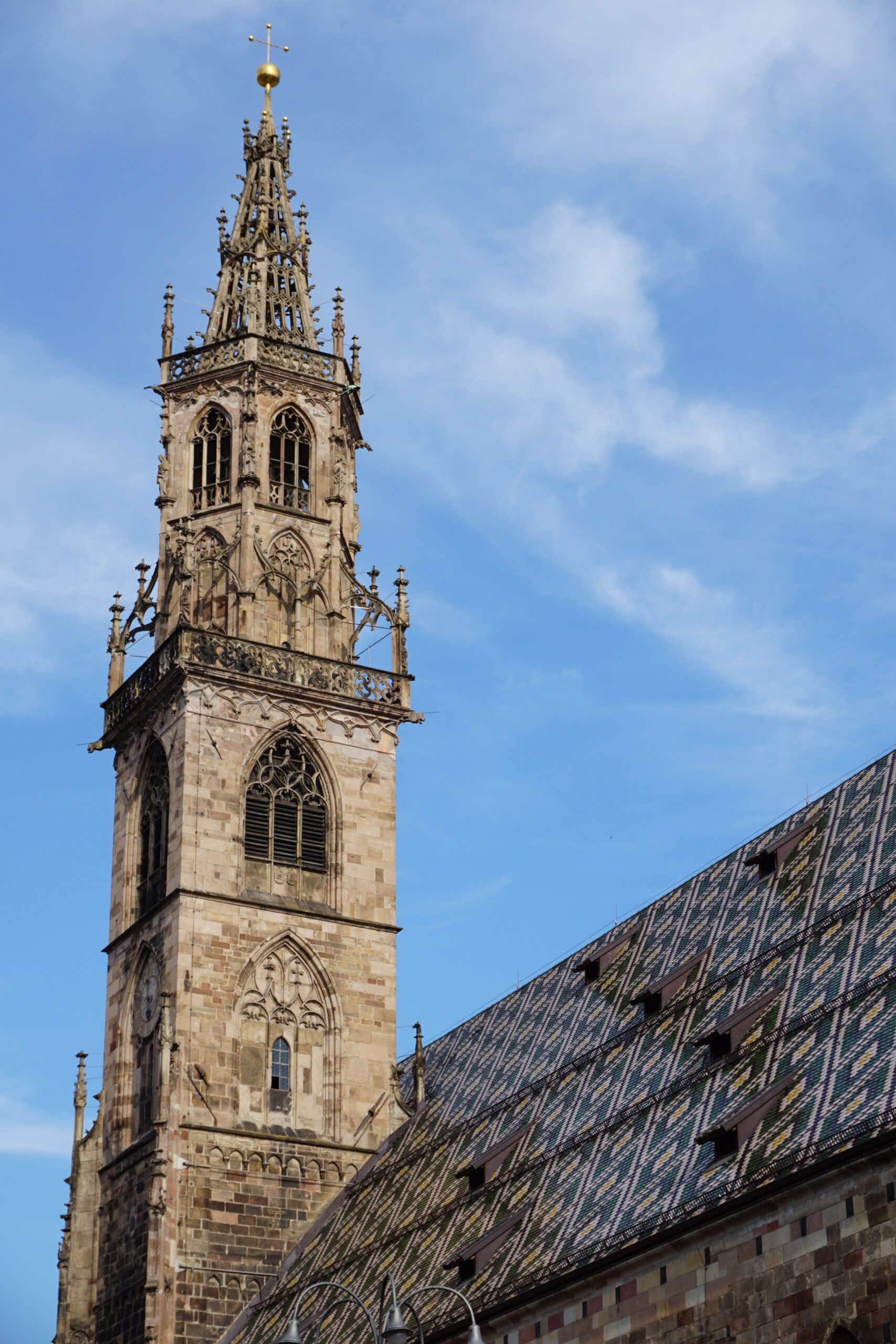 Der gotische Turm des Bozner Doms vor blauem Himmel