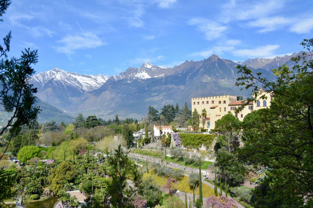 Frühlingshafte Gartenanlage in Meran mit schneebedeckten Bergen im Hintergrund